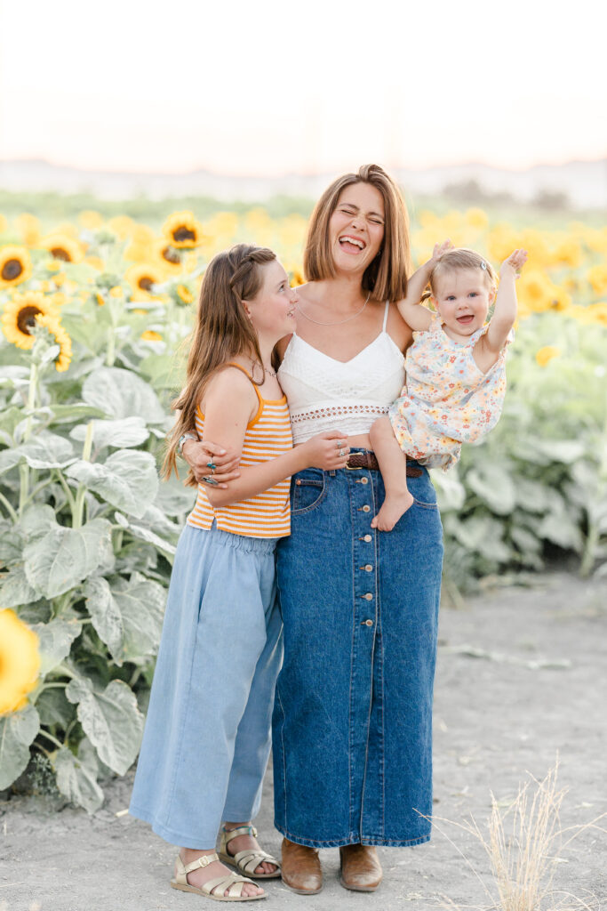 mother and daughters laughing in sunflower field